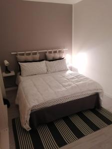 um quarto com uma cama com lençóis brancos e um tapete em Coccinella em Montesilvano