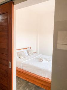 um quarto com uma cama com lençóis brancos e almofadas em Turtle House Surf & Stay em Airsatang