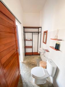 uma casa de banho com um WC e uma porta de madeira em Turtle House Surf & Stay em Airsatang