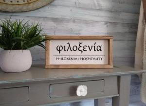 a sign on top of a table with a potted plant at Philoxenia in Kavála