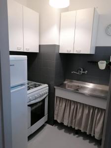 uma pequena cozinha com armários brancos e um lavatório em Coccinella em Montesilvano