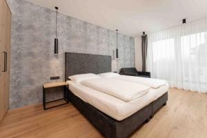 Un dormitorio con una cama grande con una pared de hormigón. en A CASA Serenity, en Serfaus