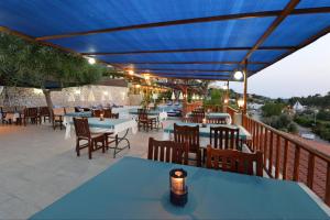 un patio con mesas, sillas y una sombrilla azul en Patara Delfin Hotel, en Patara