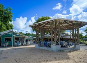 a pavilion with tables and chairs on the beach at RDC appartement en bord de mer au son des vagues in Le Moule