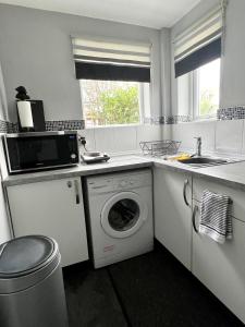 a kitchen with a washing machine and a sink at Sandford House Den in Seaford