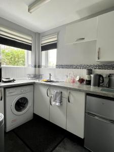 a white kitchen with a washing machine and a sink at Sandford House Den in Seaford