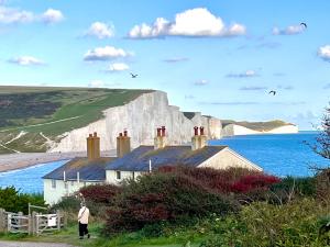a man standing next to a house in front of a white cliff at Sandford House Den in Seaford