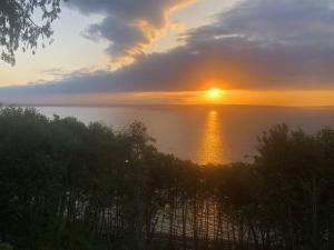 un coucher de soleil sur l'eau avec le soleil dans le ciel dans l'établissement 1-Bedroom Seaview Guesthouse on Seattle Luxury Estate with Views of Olympic Mountains, à Seattle