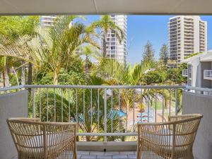 two chairs on a balcony with palm trees and buildings at Main Beach Coastal Apartment in Gold Coast