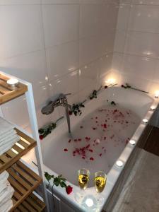 a bath tub with two glasses of wine and flowers in it at Kerekerdő Apartman - Szarvaskő in Szarvaskő +39 photos