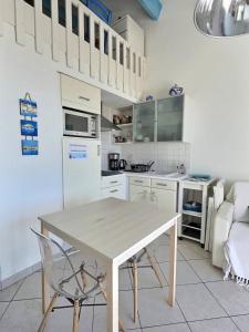 a kitchen with a table and a white refrigerator at Appartement vue mer en plein centre de Valras-Plage in Valras-Plage