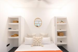 a bedroom with white walls and a bed with white shelves at Coconut Cottage - Hiriketiya Beach in Hiriketiya