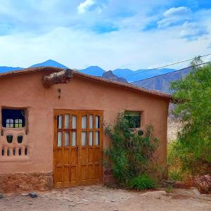 a house with a door and mountains in the background at MAMAICUNA CABAÑA in Tilcara