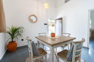 a dining room with a wooden table and chairs at Coconut Cottage - Hiriketiya Beach in Hiriketiya