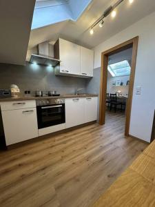 uma cozinha com armários brancos e piso em madeira em Ferienwohnung Burgunder-Paradies em Britzingen
