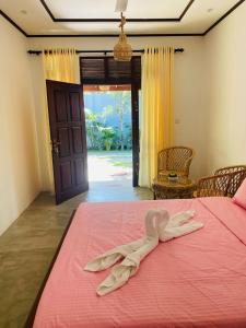 un accappatoio che giace su un letto rosa in una stanza di Abhi Villa ad Ahangama