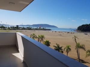 uitzicht op het strand vanaf het balkon van een gebouw bij Verdadeiro pé na areia TOP in Santos