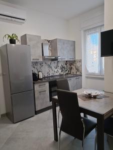 eine Küche mit einem Tisch und einem Kühlschrank aus Edelstahl in der Unterkunft Orchidea Home in Busto Arsizio