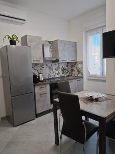 uma cozinha com uma mesa e um frigorífico de aço inoxidável em Orchidea Home em Busto Arsizio