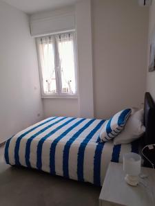 uma cama com um cobertor listrado num quarto com uma janela em Orchidea Home em Busto Arsizio mais 4 fotografias