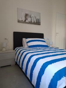 ein Schlafzimmer mit einem blau-weißen gestreiften Bett in der Unterkunft Orchidea Home in Busto Arsizio