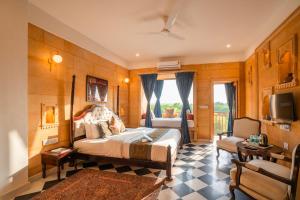 a bedroom with a bed and a tv and a couch at Hotel Helsinki House in Jaisalmer