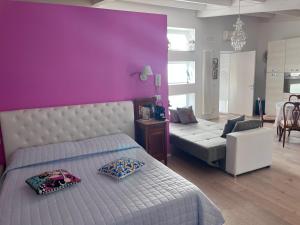 1 dormitorio con pared morada, cama y sofá en B&B dell'orologio, en Acquaviva delle Fonti