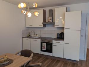 cocina con armarios blancos y mesa de madera en Moderne Neubau Ferienwohnung en Wiesbaden