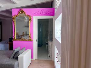 een slaapkamer met een roze muur en een spiegel bij B&B dell'orologio in Acquaviva delle Fonti