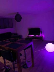 um quarto roxo com uma mesa e uma televisão em L'appartement charmant em Beynost