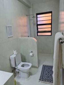 a white bathroom with a toilet and a window at The Landing Cottages in Nanyuki