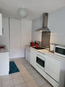 eine Küche mit weißen Schränken und einem Herd in der Unterkunft Maisonette moderne T2 65 m2 -Eyragues in Eyragues