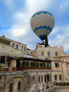 a blue and white hot air balloon flying over a building at Century Cave Hotel in Göreme