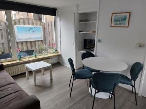 a living room with a table and chairs and a window at Huize Visser in Egmond aan Zee