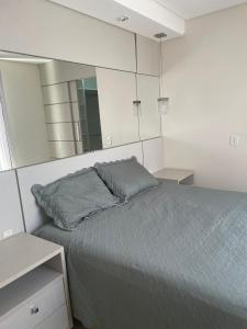 ein Schlafzimmer mit einem Bett und einem großen Spiegel in der Unterkunft Cobertura com duas vagas de garagem in Bombinhas