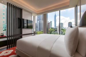 Hotel Indigo Kuala Lumpur on the Park, an IHG Hotel في كوالالمبور: غرفة نوم بسرير ابيض كبير ونافذة كبيرة