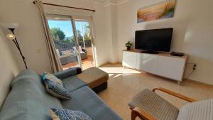 salon z niebieską kanapą i telewizorem w obiekcie Rico Apartaments Ricosol w mieście Torrox Costa