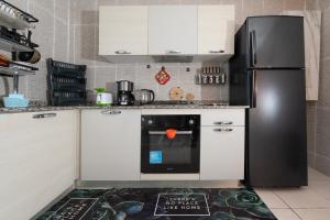 a kitchen with a black refrigerator and white cabinets at Appartement en résidence avec piscine in Agadir
