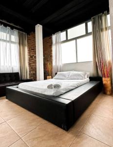 a large black bed in a room with windows at Villa tikuna in Mariquita
