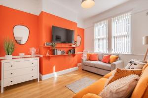 a living room with an orange wall at Stunning 2BD Stay in Carlisle! in Carlisle