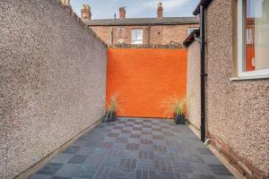 alejka pomiędzy dwoma budynkami z pomarańczową ścianą w obiekcie Stunning 2BD Stay in Carlisle! w mieście Carlisle