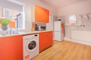 an orange kitchen with a washing machine and a refrigerator at Stunning 2BD Stay in Carlisle! in Carlisle