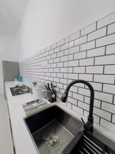 a kitchen with a sink and a white brick wall at NOOR Homestay Paddy View in Kangar