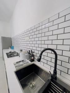 a kitchen with a sink and a white brick wall at Paddy View Homestay in Kangar