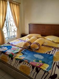 a bed with a comforter and pillows on it at Villa Highland No 8 Berastagi View in Berastagi