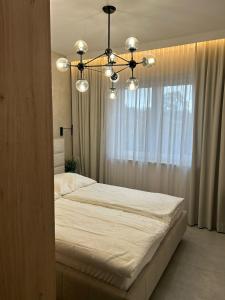 Un dormitorio con una cama grande y una lámpara de araña. en Luxury Apartments Słupsk, en Słupsk