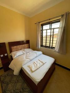 Schlafzimmer mit einem Bett mit weißer Bettwäsche und einem Fenster in der Unterkunft Getaway bnb - Njombe in Njombe