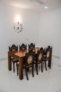 a dining room table with chairs and a clock on the wall at Villa Double T Residence in Ambalangoda