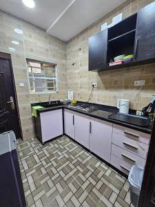 a kitchen with white cabinets and a black counter top at APARTMENT 001 in Lagos