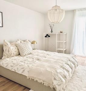 ein weißes Schlafzimmer mit einem großen Bett und einer Lampe in der Unterkunft Haus am Bodensee mit Sicht - Stilvoller Luxus in Ermatingen